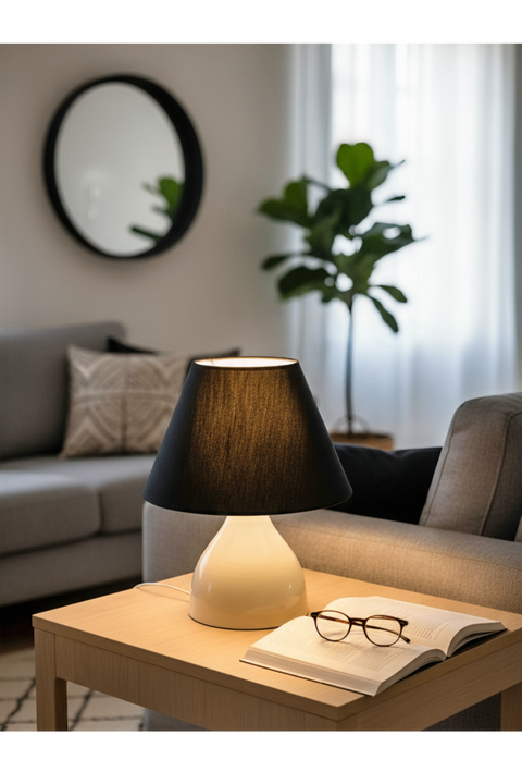 Lamp on a coffee table in a living room with a book and glasses