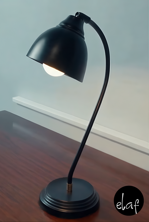 Matte black vintage-style desk lamp with curved metal neck and adjustable head, placed on wooden desk surface