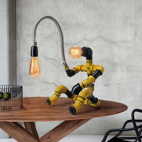 Industrial-style table lamp shaped like a fisherman holding a light bulb, made from metal pipework