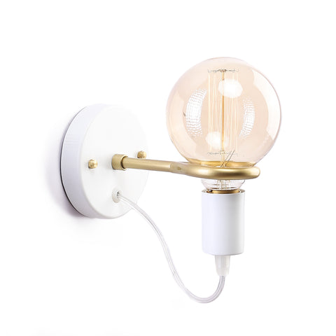 White and gold wall sconce with round base and exposed globe bulb, mounted on light-colored wall for soft modern lighting